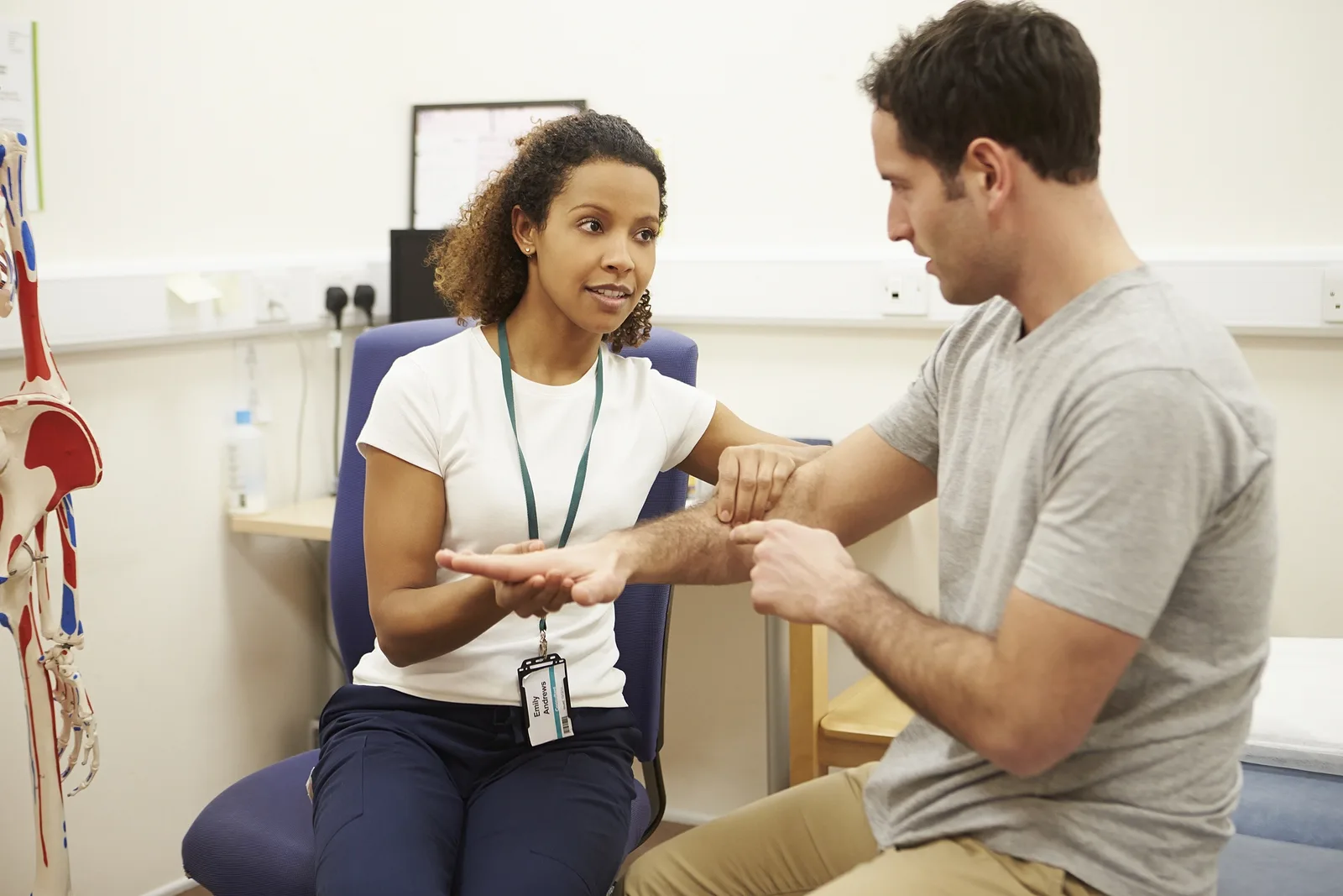 Physiotherapist examining a patient's hand in a treatment room
