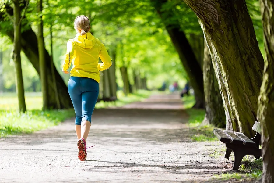 Runner jogging along a tree-lined path in a park