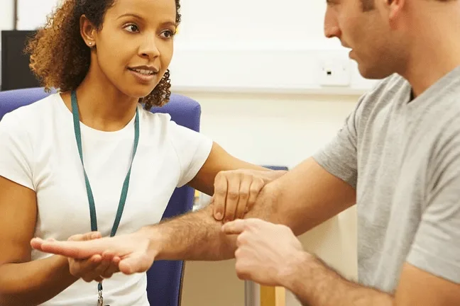 Physiotherapist and patient discussing an arm injury